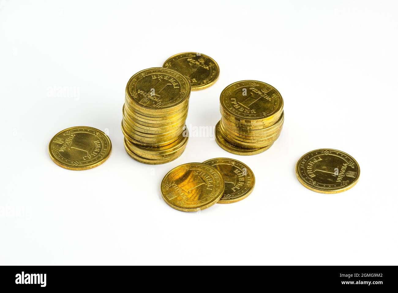Monete di ferro giallo in denominazione di 1 hryvnia giacciono alla rinfusa e impilate su uno sfondo bianco di taglio Foto Stock