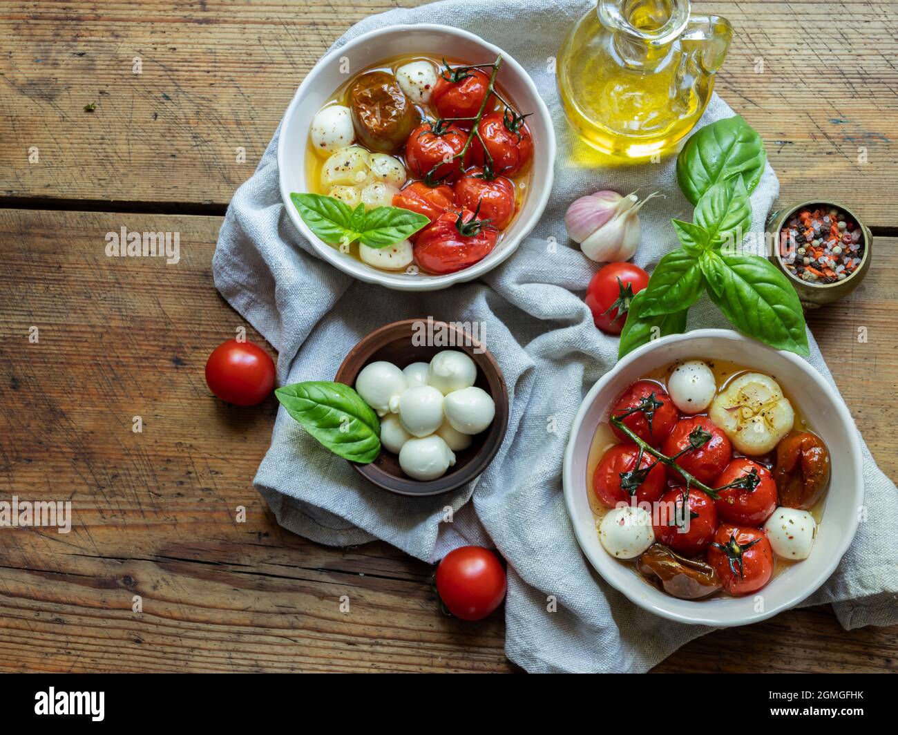 Insalata. Pomodoro al forno, basilico, aglio con mozzarella in piatti di ceramica. Cucina, piatto vegetariano cotto Foto Stock