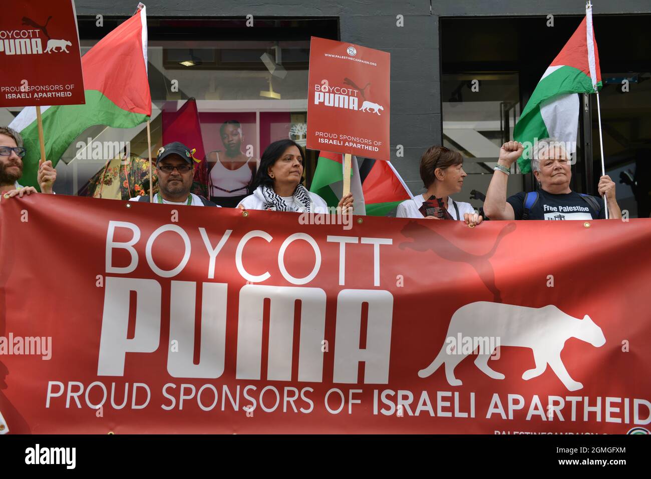 Manifestanti che tengono cartelli e bandiere, durante la dimostrazione. Boicottaggio protesta Puma organizzata dalla Palestine Solidarity Campaign e FOA (Friends of al Aqsa) presso il negozio di punta Puma a Carnaby Street, Londra. Foto Stock