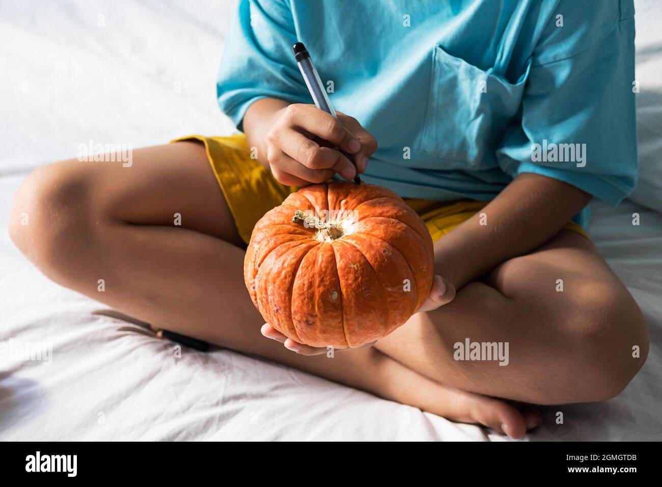 Ragazzo che fa Jack-o-Lanterna a casa. Concetto di DIY di Halloween. Foto Stock