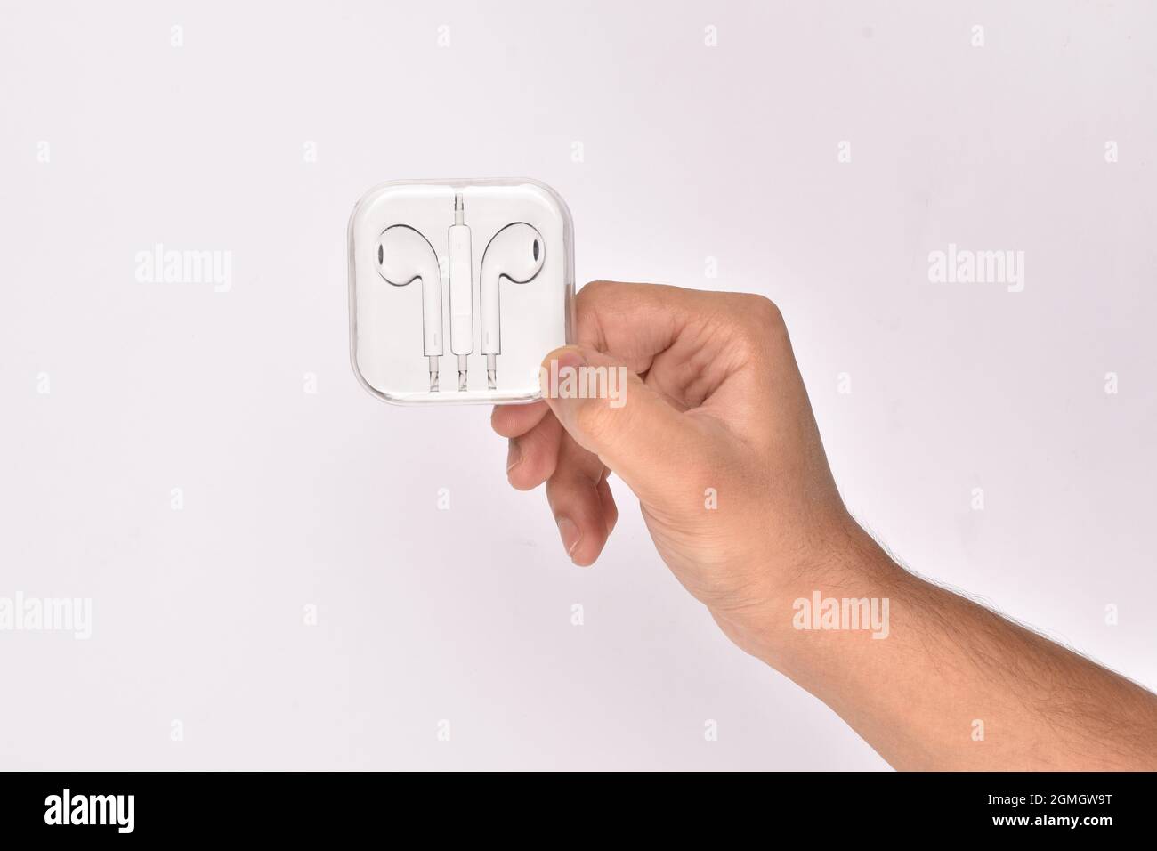 mano che tiene il nuovo paio di auricolari su sfondo bianco Foto Stock