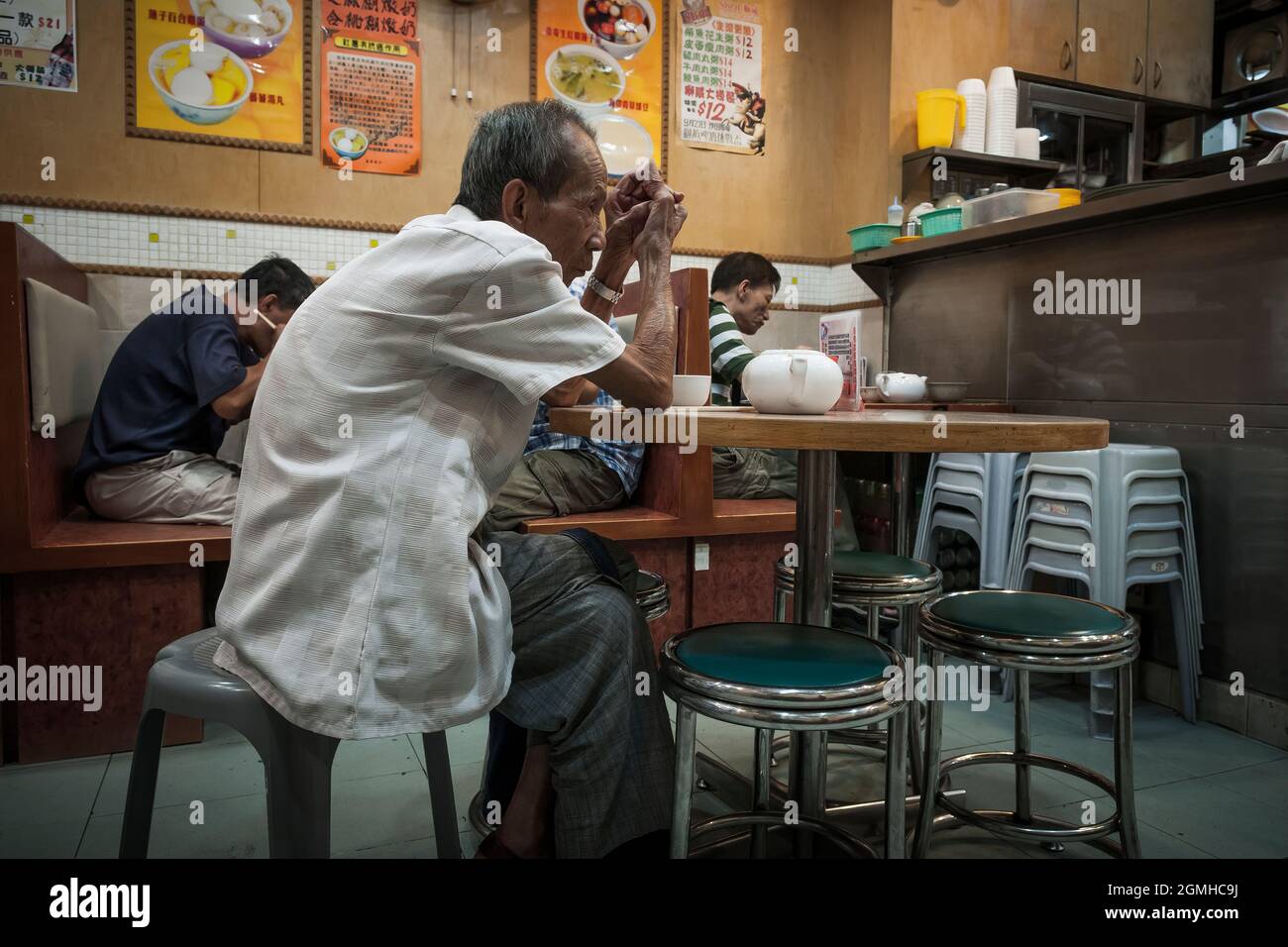 Un uomo anziano aspetta il suo cibo in un ristorante a Yuen Long, New Territories, Hong Kong Foto Stock