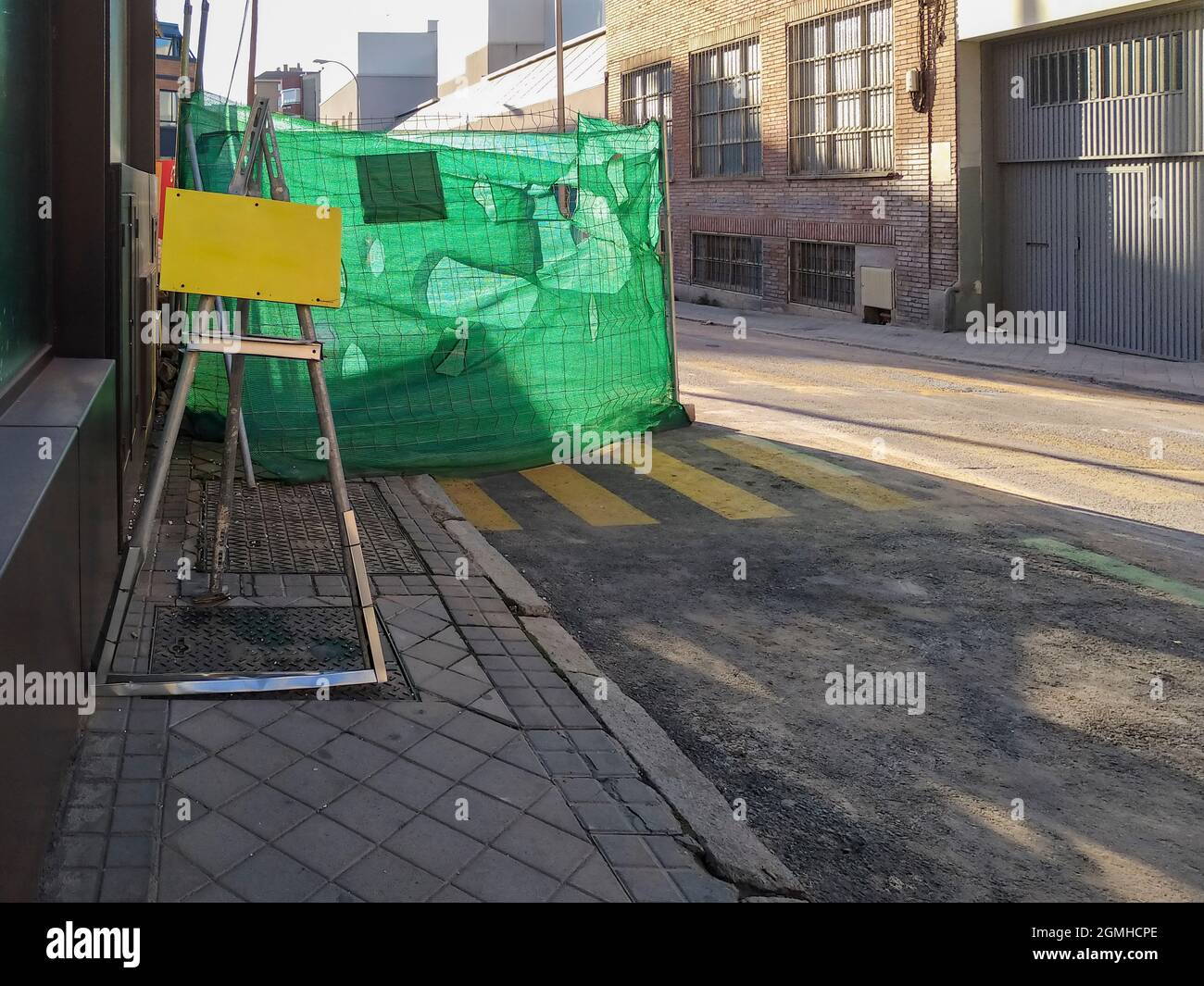 Cartello vuoto di fronte a una zona di lavoro recintata per la manutenzione stradale su una strada della città Foto Stock