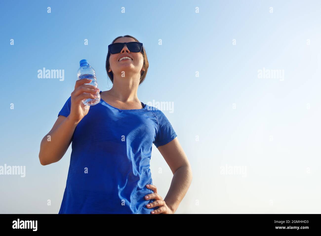 fitness donna con bottiglia di acqua potabile sulla spiaggia di mare Foto Stock