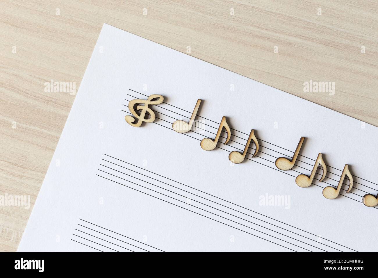 Note musicali in legno adagiate su un tavolo luminoso Foto Stock