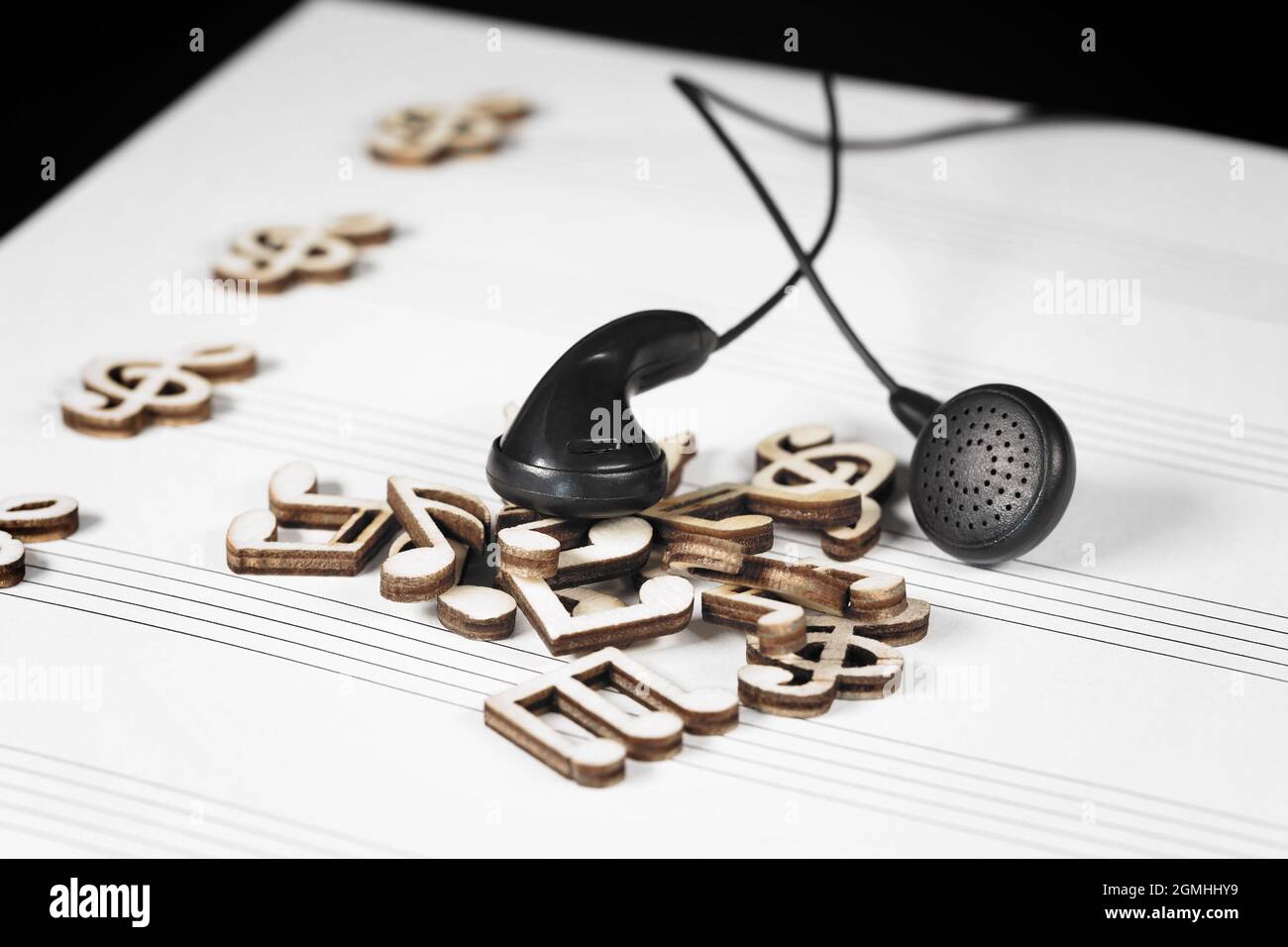 Note musicali in legno heap con cuffie nere. Foto Stock