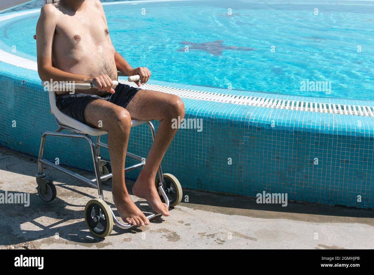 Uomo disabili in ascensore per sedie a rotelle e trasferimento in acqua da un assistente. Foto Stock