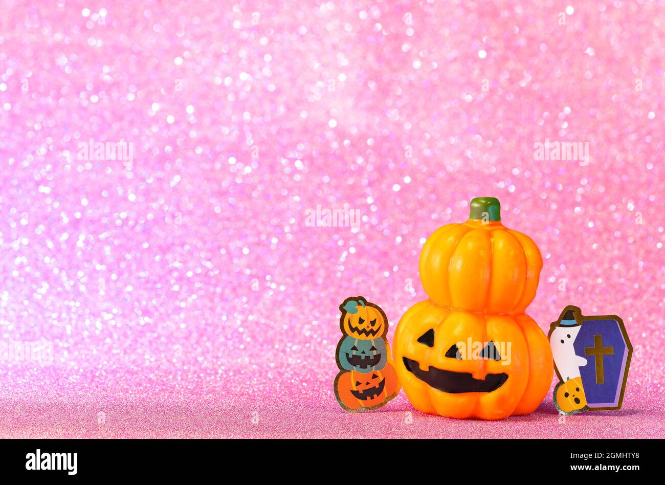 Fotografia di studio che raffigura una testa di zucca sorridente di Halloween jack o lanterna con un taglio di cartone di un fantasma divertente che tiene una bara cristiana contro Foto Stock