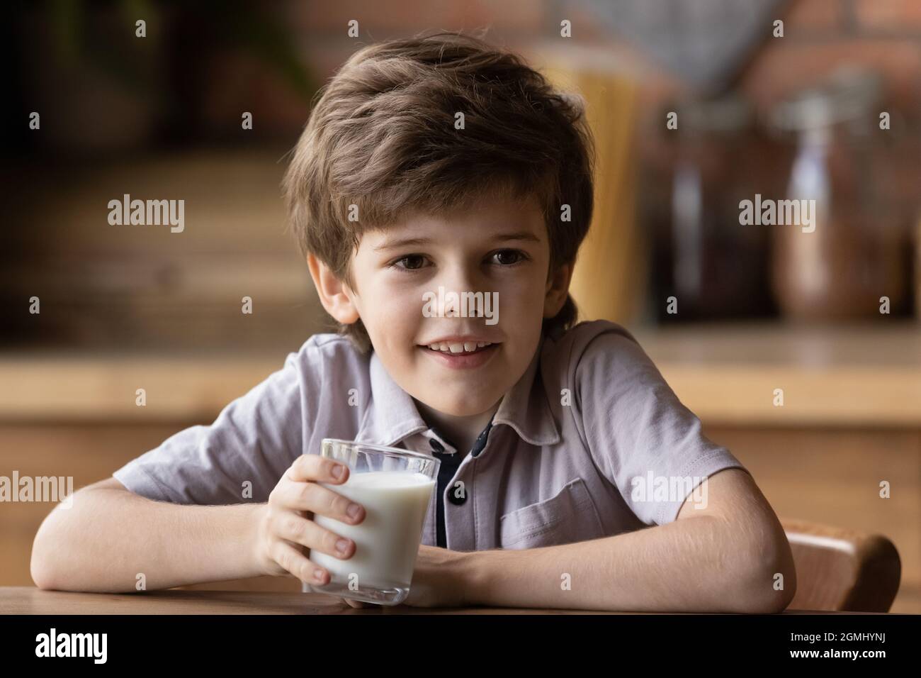 Sorridente ragazzino carino che beve yogurt biologico. Foto Stock