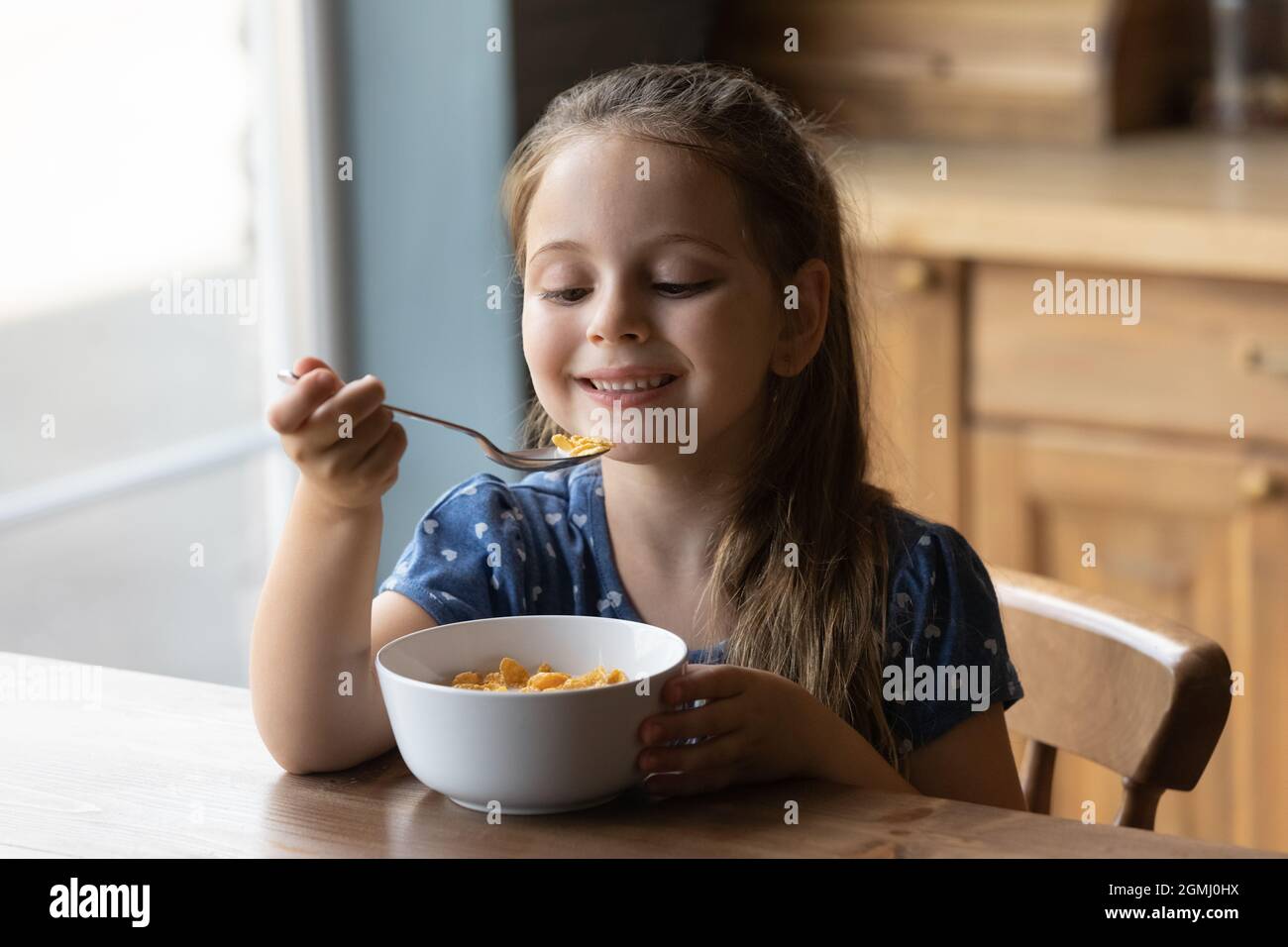 Felice piccola ragazza carina bambino che mangia croccante pasto secco veloce. Foto Stock