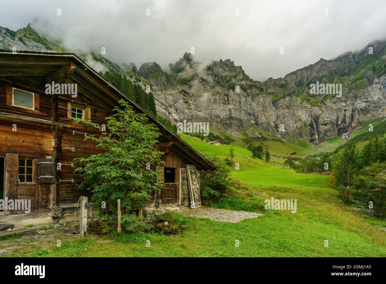Alphütten ad Adelboden, Schweiz. Fattoria alpina boscosa su prato verde su ripido pendio nella valle di Adelboden. Landschaft im Berner Oberland Foto Stock
