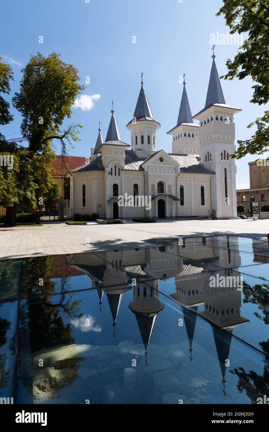 Foto frontale della Chiesa di Santo Stefano la cui riflessione si può vedere nella finestra che protegge i resti medievali della vecchia chiesa. Baia Mare Foto Stock
