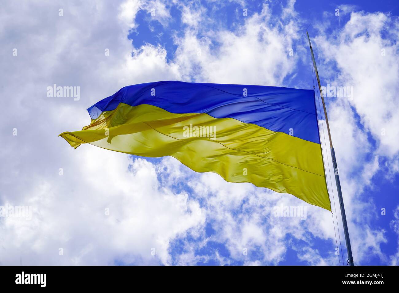 La bandiera giallo-blu dell'Ucraina sbatte contro il cielo blu. Simbolo ucraino. Una grande bandiera su un flagpole sbatte nel vento Foto Stock