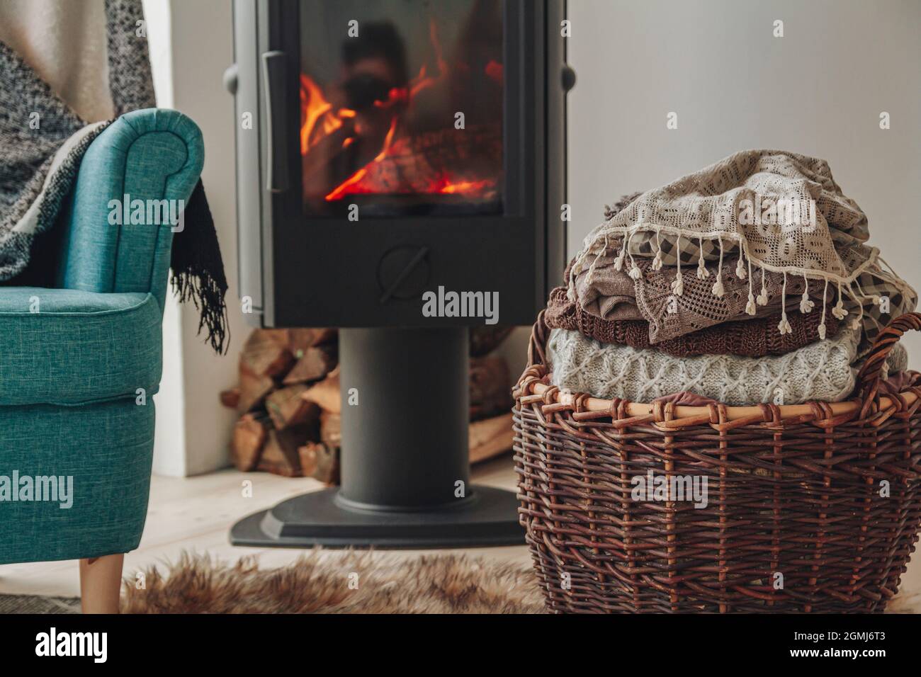 Una pila di vestiti caldi in un cesto di vimini un camino di ferro wit Foto Stock