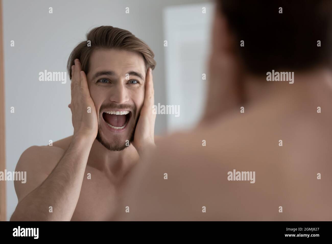 L'uomo guarda nello specchio urlando ritiene sollecitato dovuto disordine della pelle Foto Stock