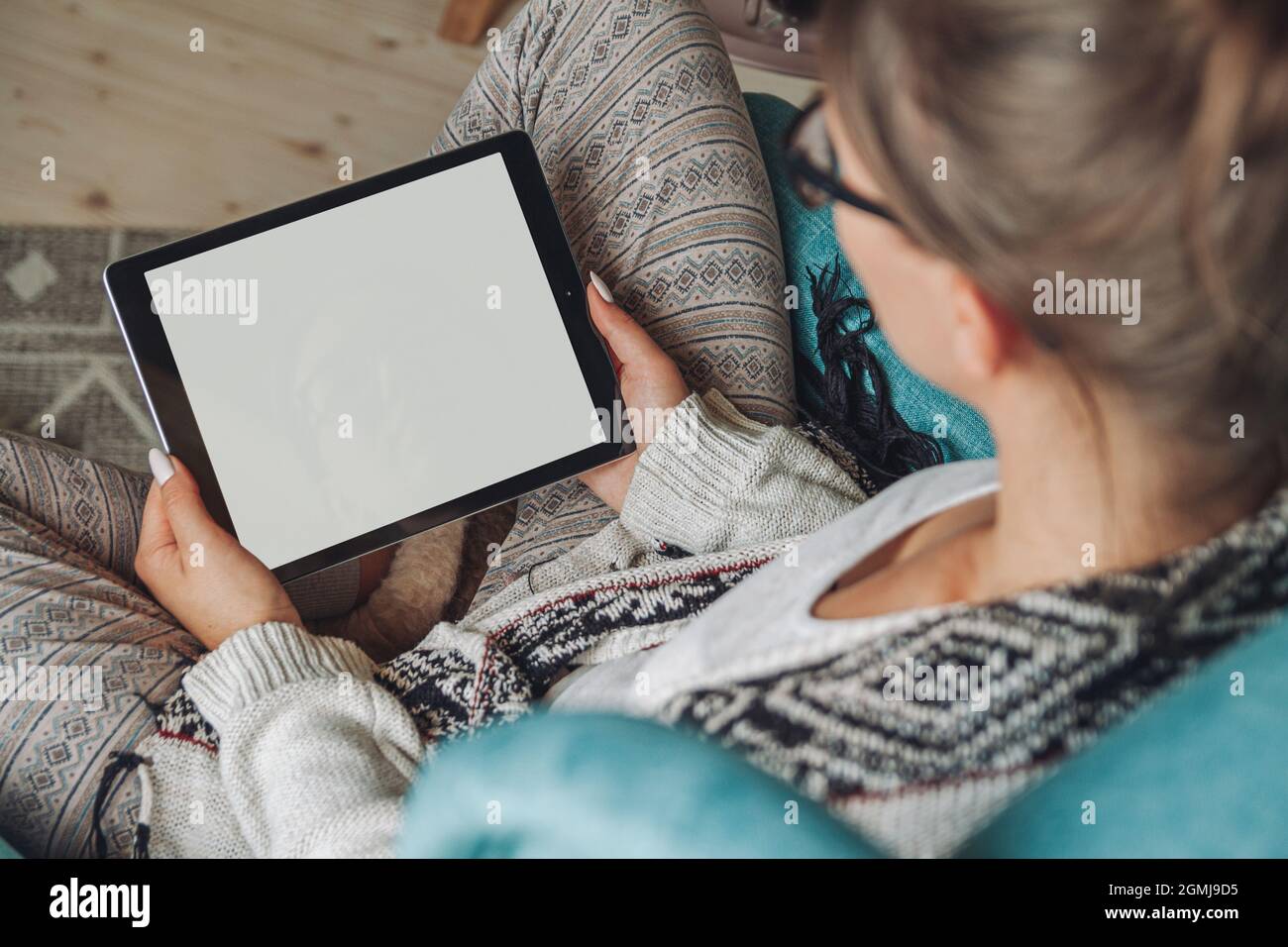 donna seduta in comoda poltrona, con coperta calda, con tablet Foto Stock