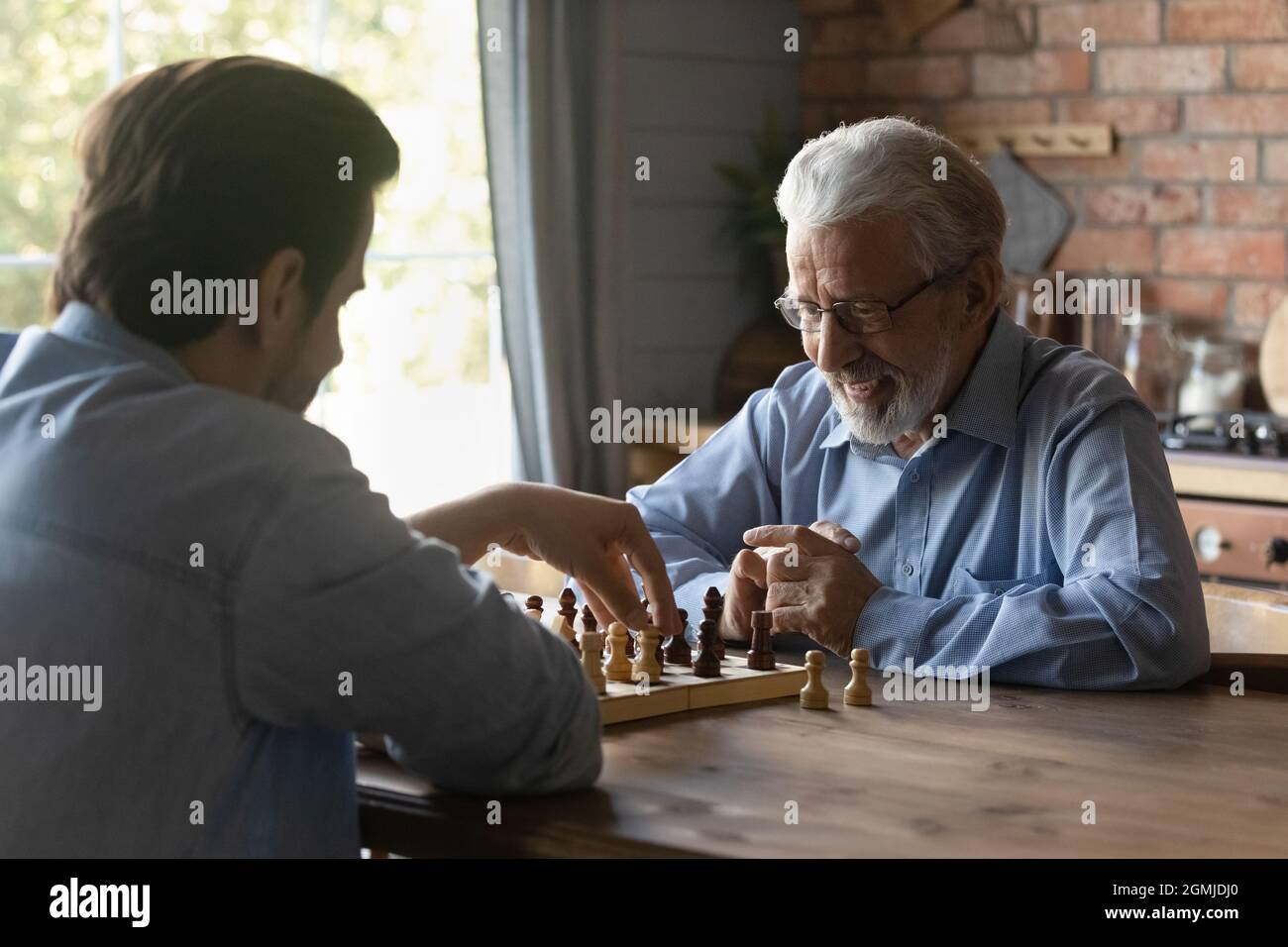 Uomo maturo sorridente con figlio grownup che gioca a scacchi insieme Foto Stock