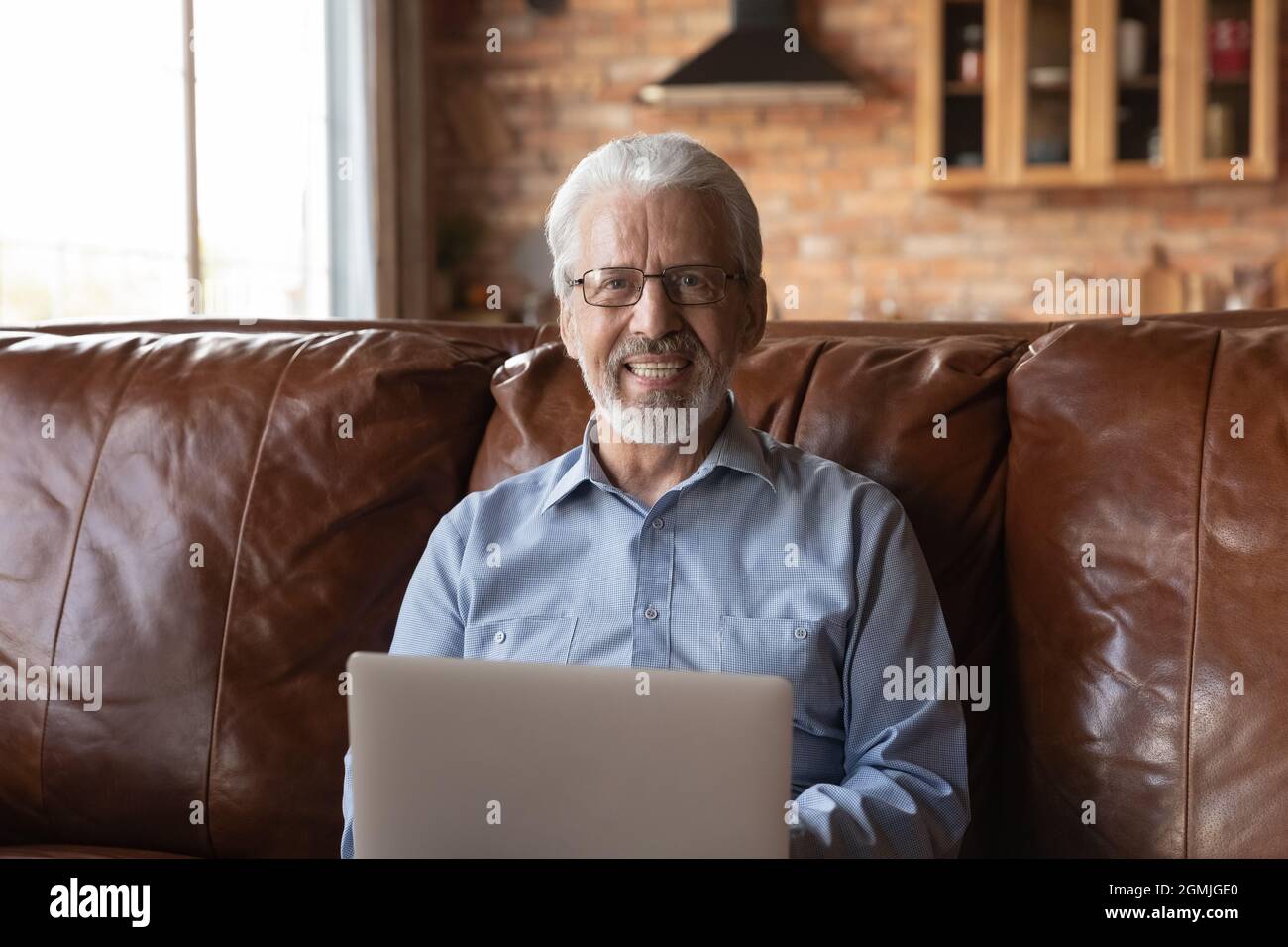 Testa ritratto sorridente uomo anziano in occhiali utilizzando il laptop Foto Stock