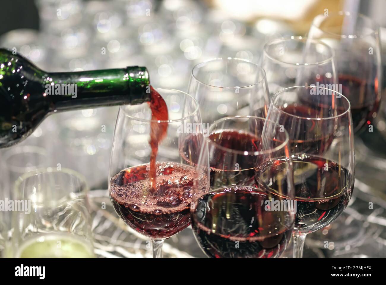 versare il vino in molti bicchieri per la cena, girando a fuoco stretto. Foto Stock