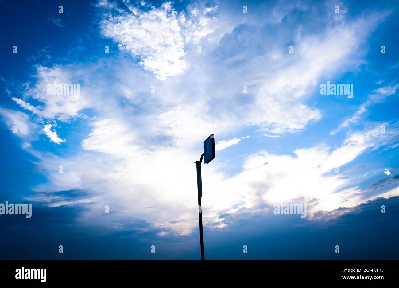 Cartello su palo su sfondo blu chiaro poco nuvoloso Foto Stock