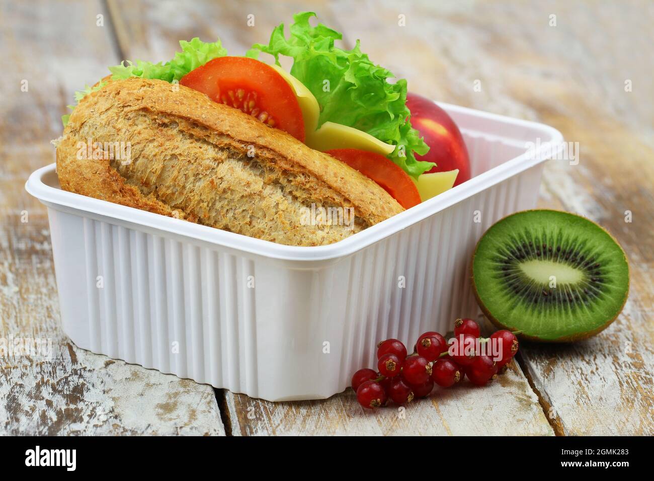 Scatola per il pranzo della scuola sana contenente sandwich di formaggio a grani interi, frutta di mela e kiwi Foto Stock