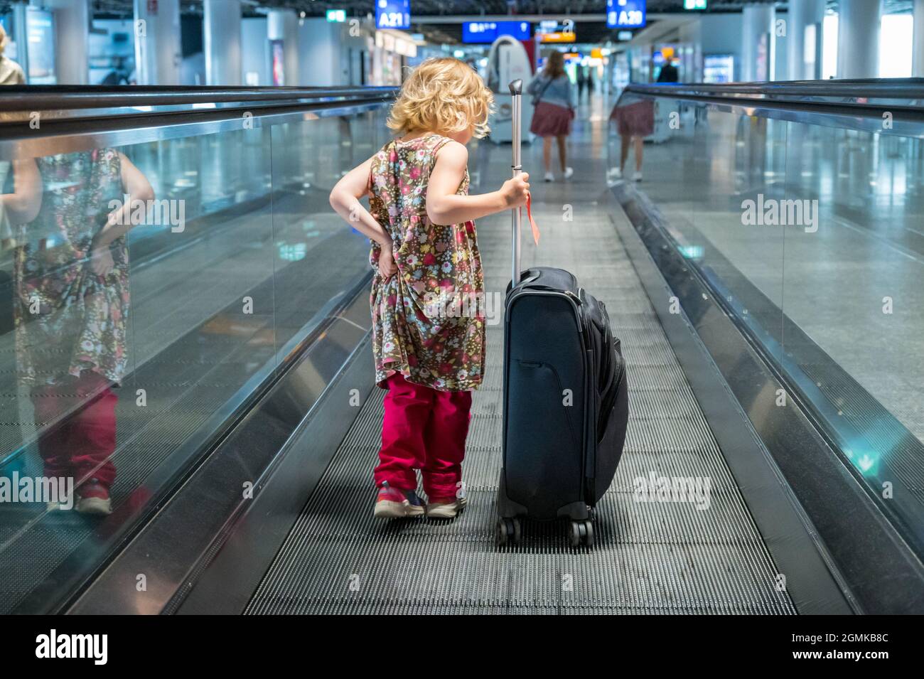 Ragazza bionda carina con bagaglio da viaggio all'aeroporto. Foto Stock