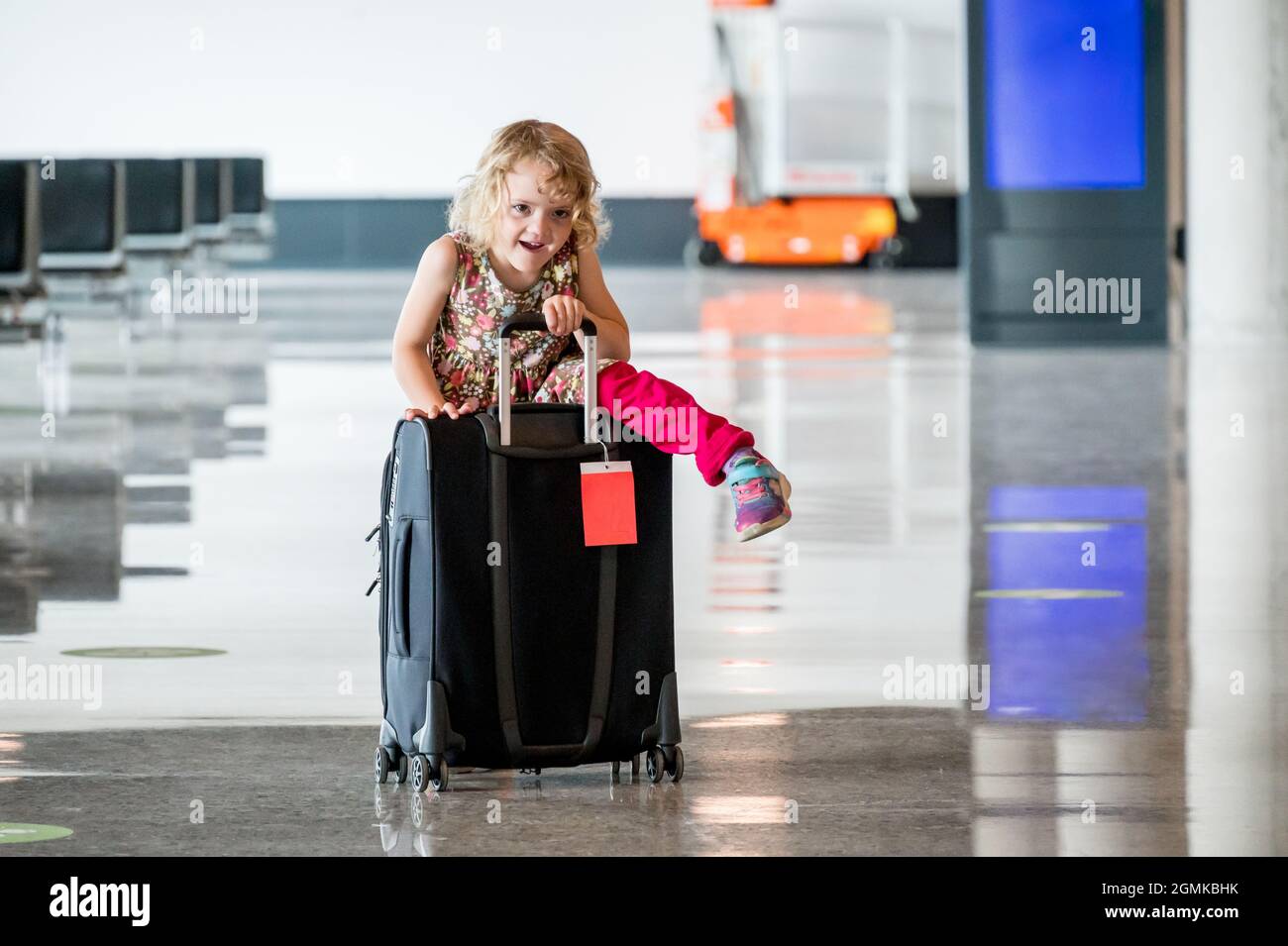 Ragazza bionda carina con bagaglio da viaggio all'aeroporto. Foto Stock