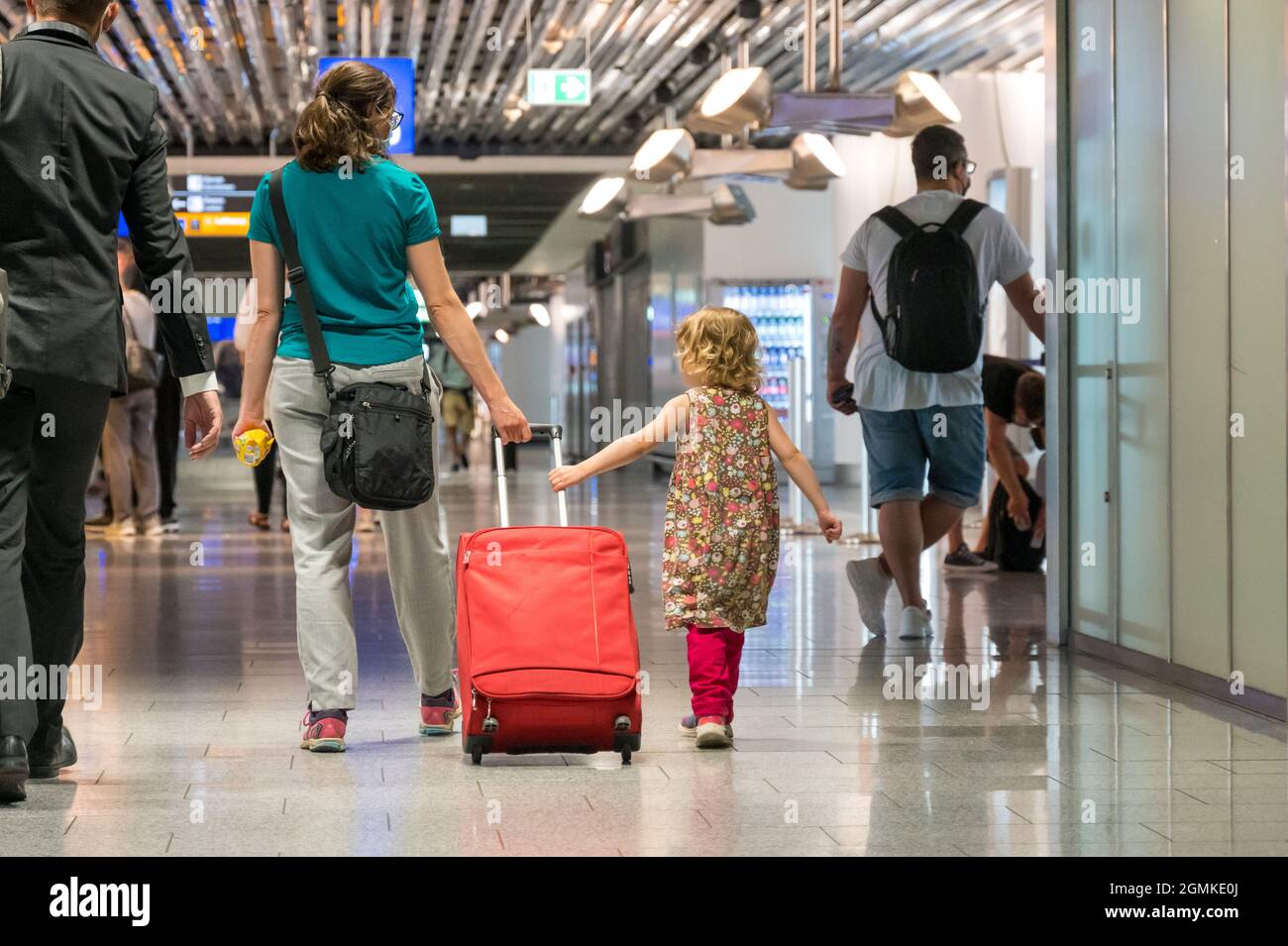 Vista posteriore di madre e figlia con bagaglio viaggiante che cattura un aereo. Foto Stock