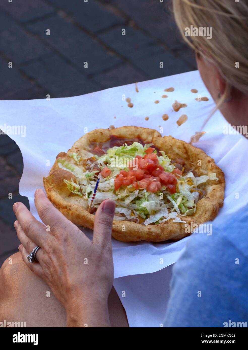Una donna si prepara a mangiare un taco indiano, un piatto di fast food regionale preferito, al Fiesta de Santa Fe a Santa Fe, New Mexico. Foto Stock