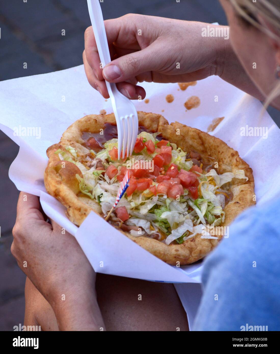 Una donna si prepara a mangiare un taco indiano, un piatto di fast food regionale preferito, al Fiesta de Santa Fe a Santa Fe, New Mexico. Foto Stock