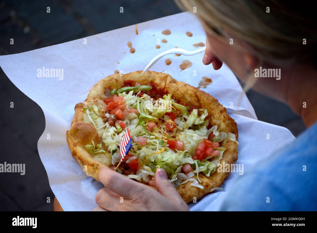 Una donna si prepara a mangiare un taco indiano, un piatto di fast food regionale preferito, al Fiesta de Santa Fe a Santa Fe, New Mexico. Foto Stock