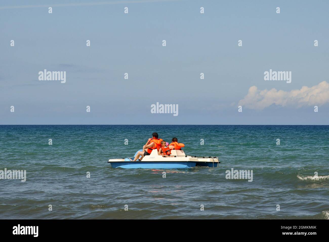 Una famiglia in vacanza pedalò sulla riva del mare in una giornata estiva soleggiata con cielo blu, San Vincenzo, Livorno, Toscana, Italia Foto Stock