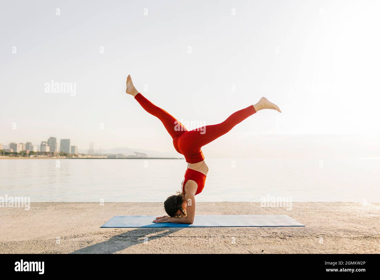 Atletica giovane ispanica in abbigliamento sportivo rosso che fa yoga al mattino Foto Stock