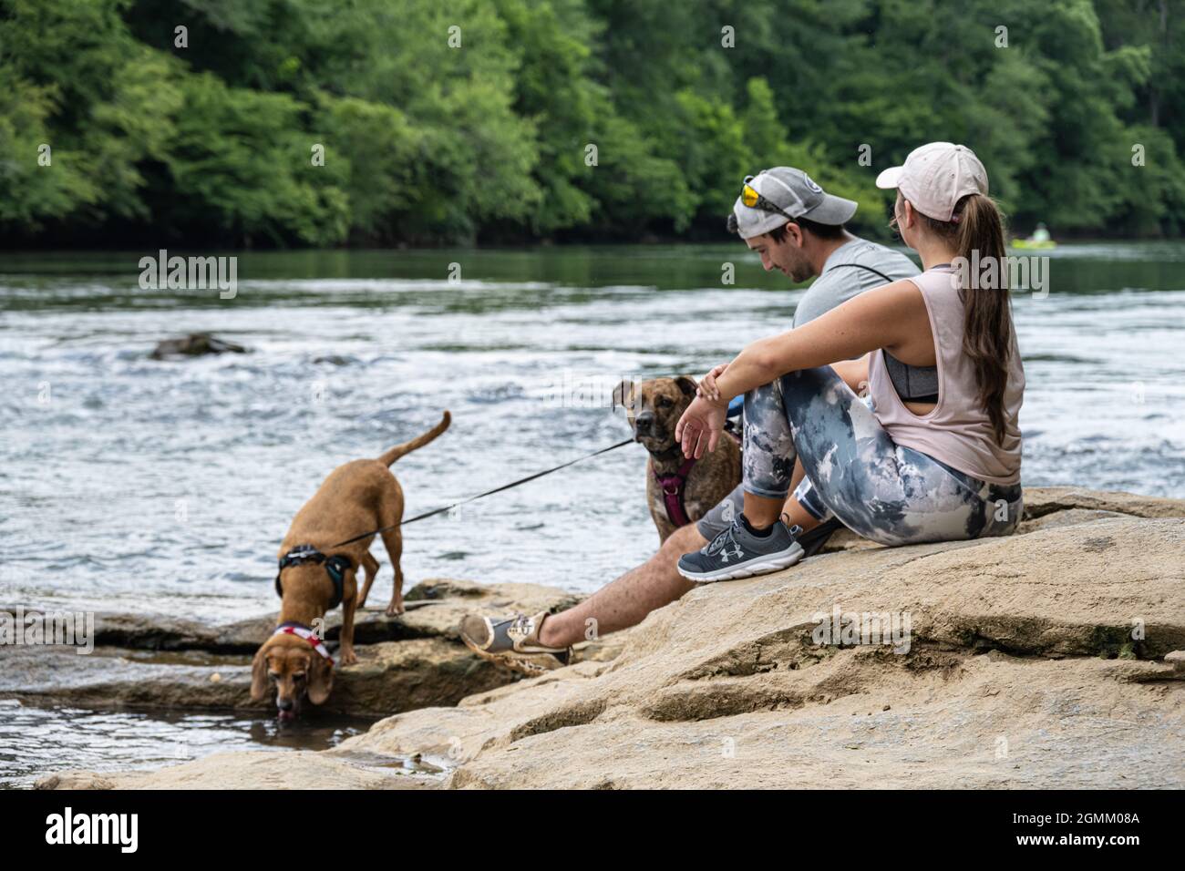 Coppia con cani rilassarsi lungo la costa rocciosa del fiume Chattahoochee a Sandy Springs, appena a nord di Atlanta, Georgia. (USA) Foto Stock
