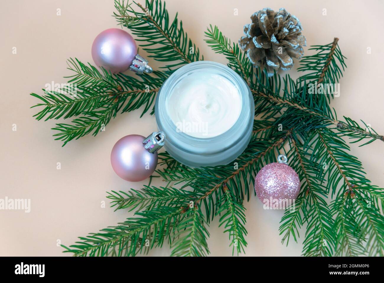 Vaso crema aperto con rami di abete e palle di Natale decorativo piatto sfondo. Pubblicità cosmetica stagione invernale, vista dall'alto Foto Stock