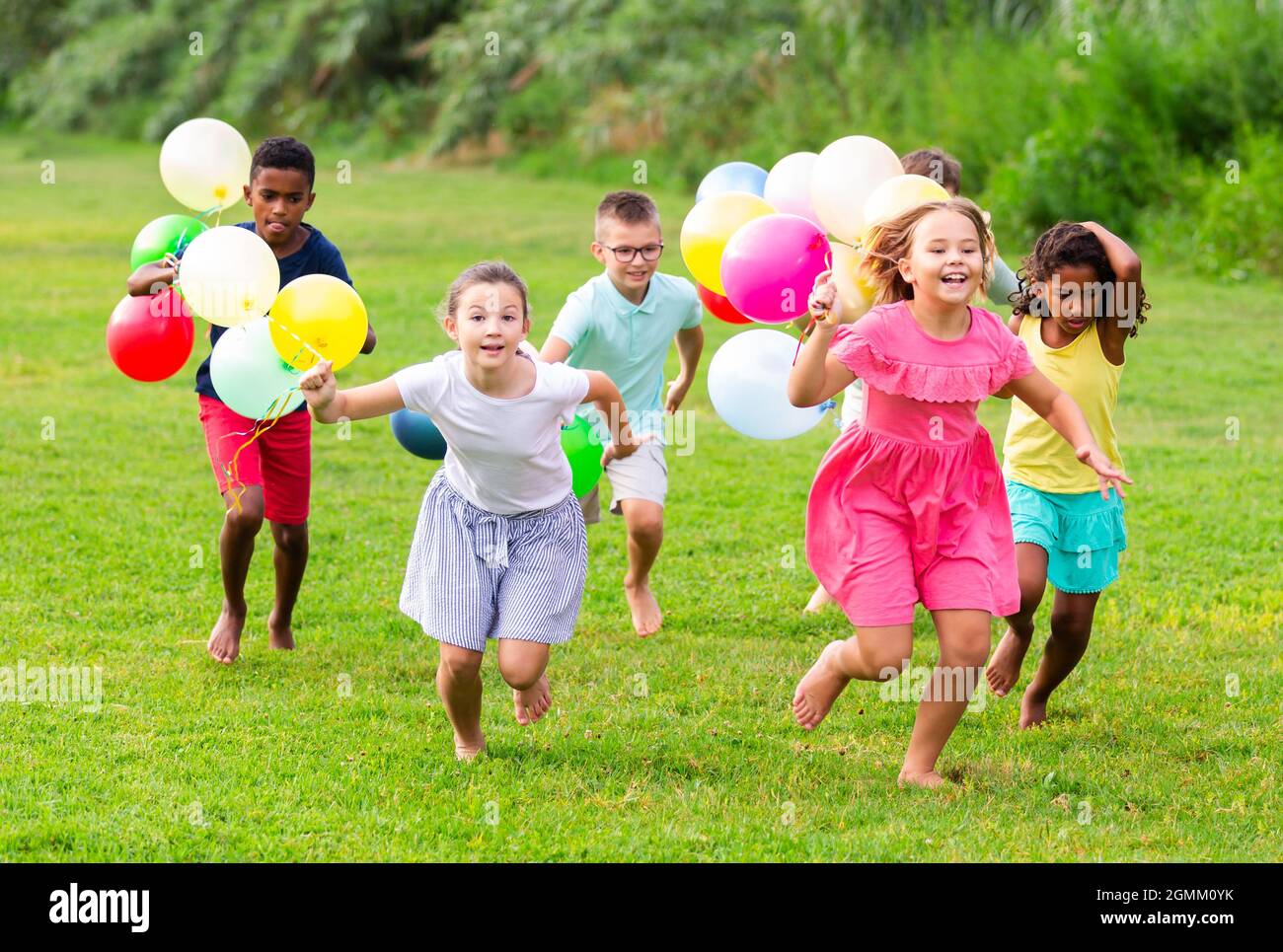 Bambini con palloncini che attraversano il campo Foto Stock