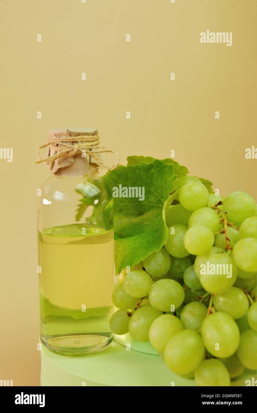 Bottiglia d'olio di semi d'uva e mazzo di uve verdi sul podio. Olio di semi di uva Bio naturale biologico. Foto Stock
