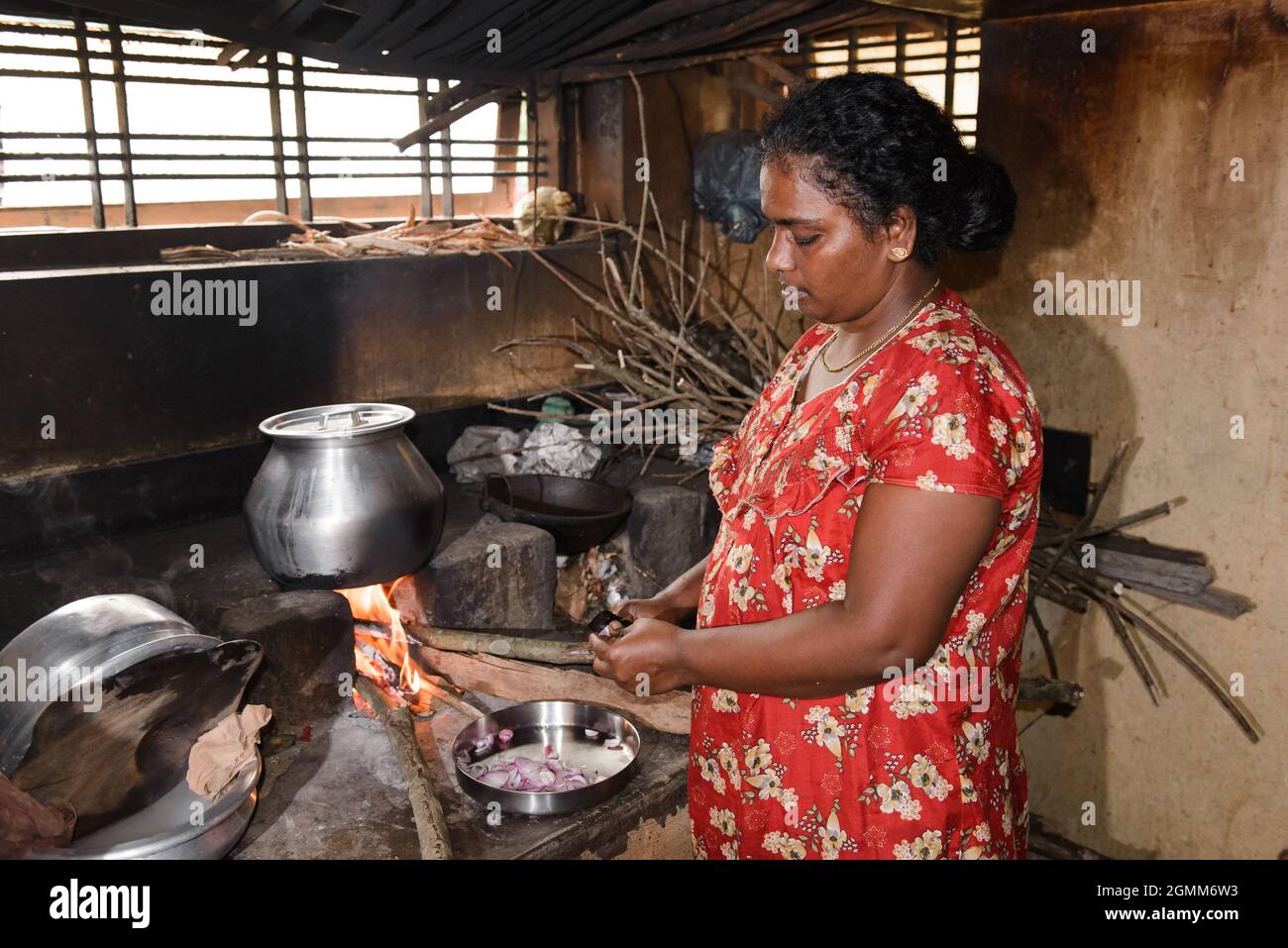 Aranmula, India - 5 dicembre 2015: Donna indiana che cucina cibo in stufa in casa rurale al mattino sopra la finestra. Semplice vivere in Asia Foto Stock