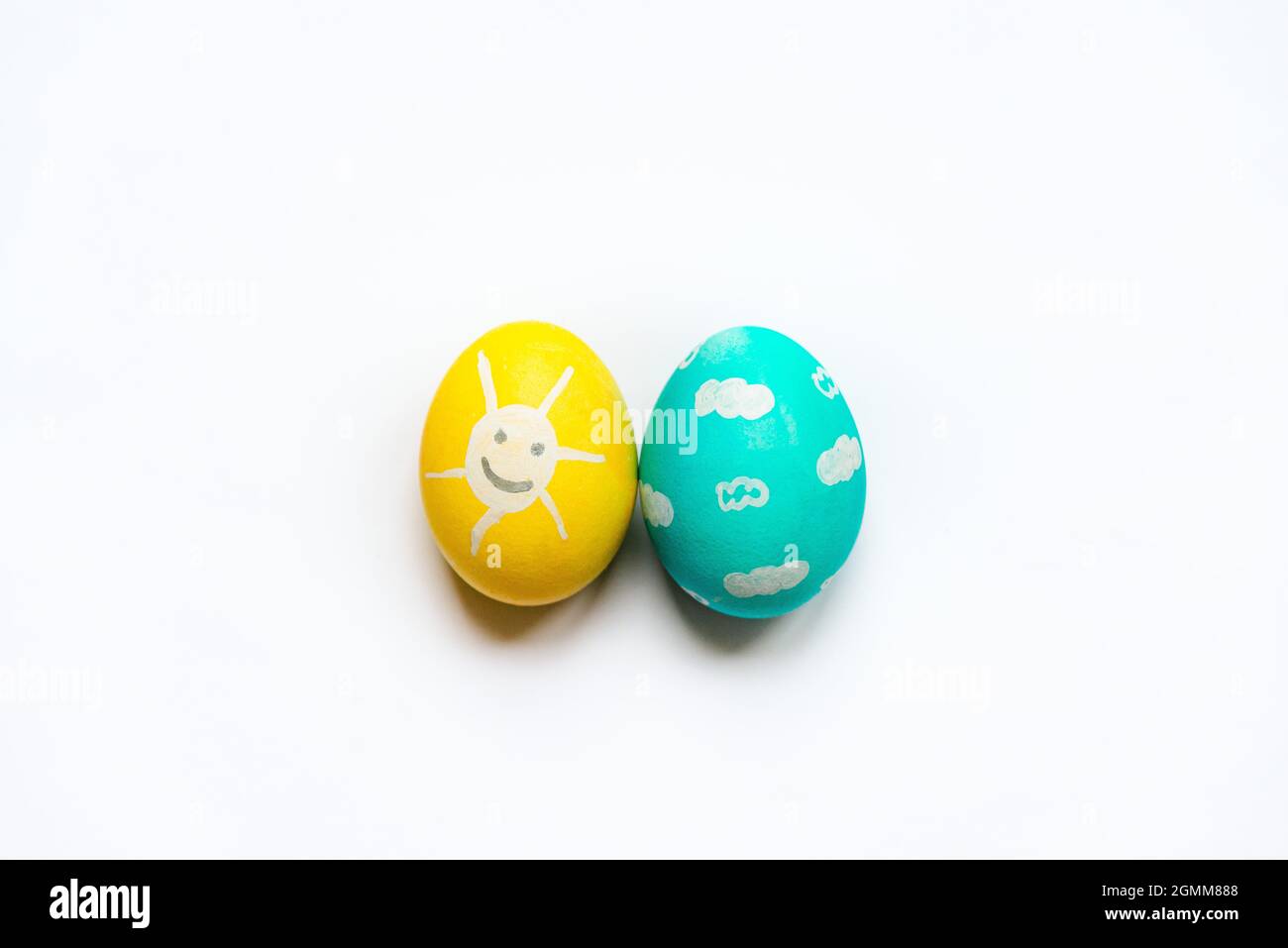 Una serie di uova di Pasqua colorate dipinte come sole sorridente e cielo blu. Foto Stock