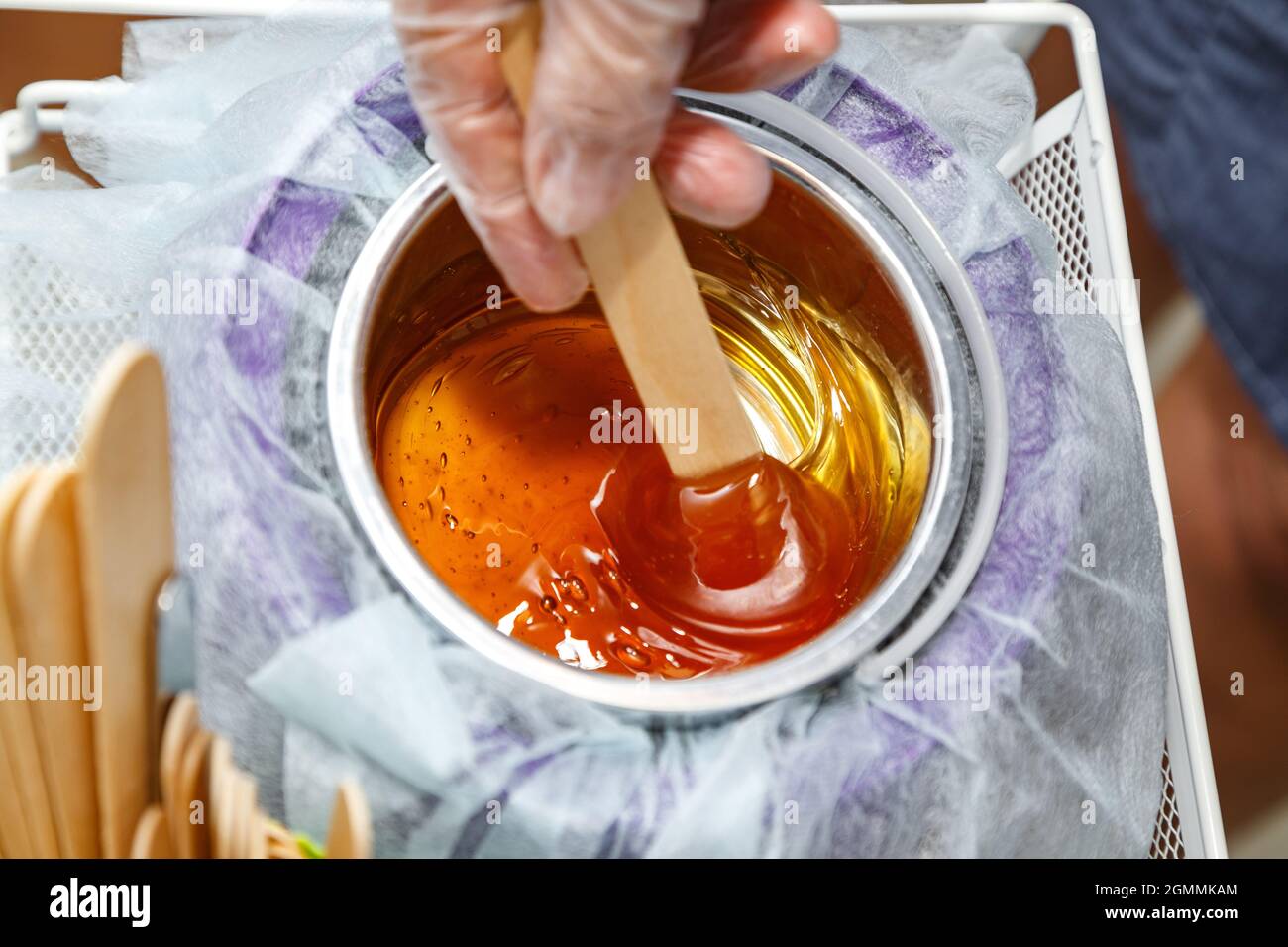 Foto di cera di miele fusa su bastone di legno per depilazione Foto Stock