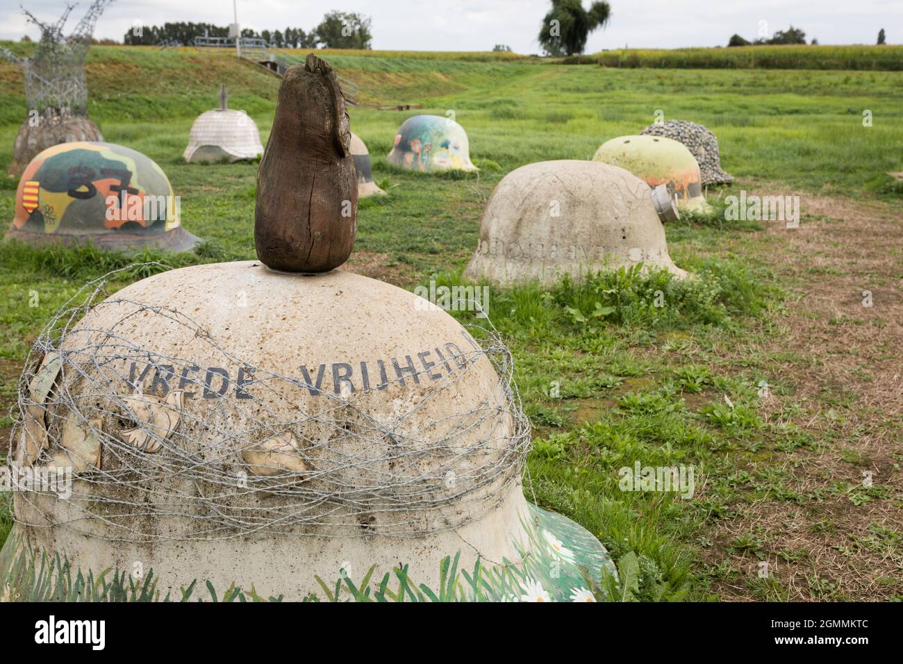 Monumento della prima guerra mondiale con caschi in cemento in un paesaggio in Belgio, testo casco: Pace libertà Foto Stock
