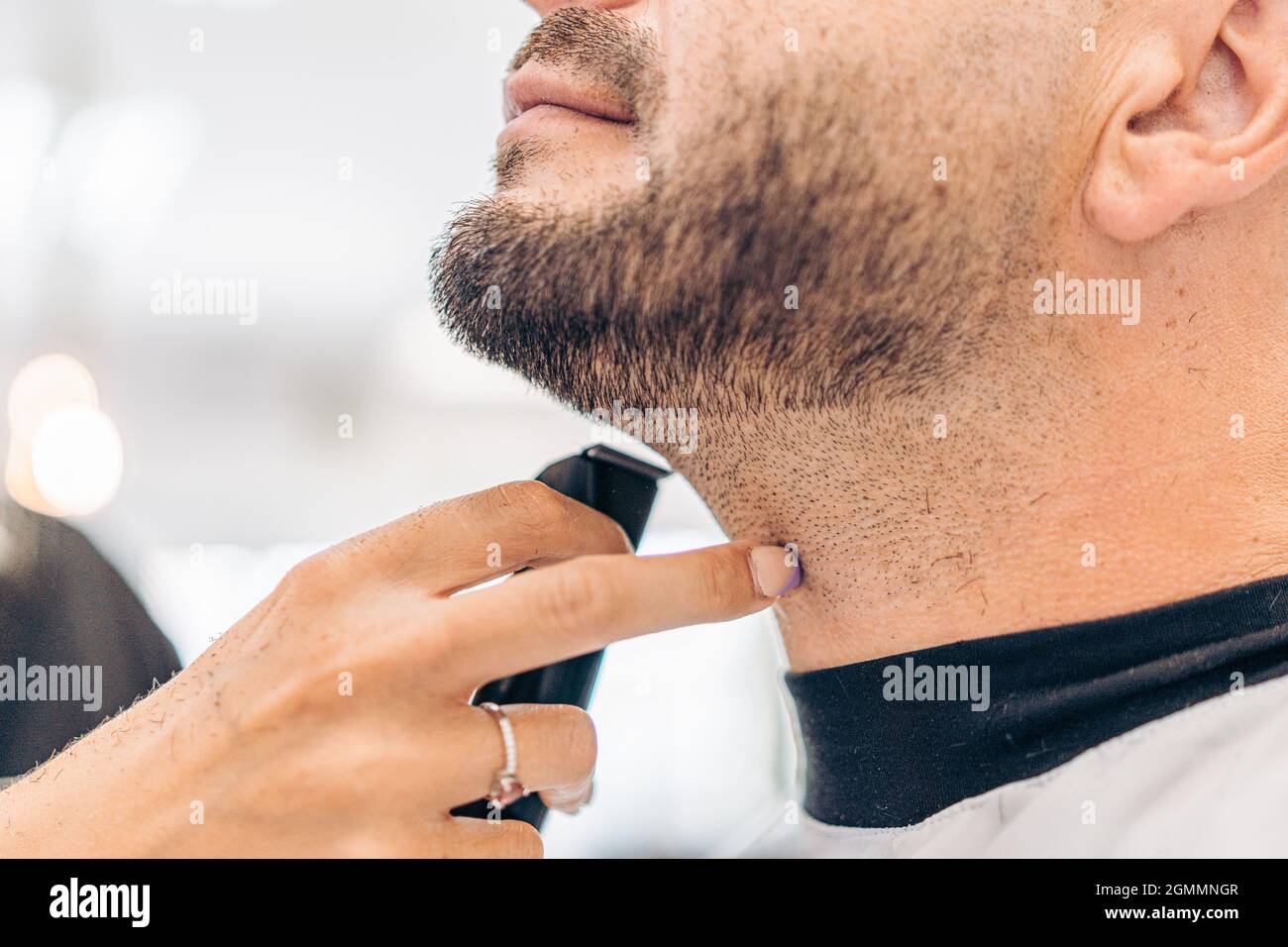 Dito di una donna che punta una barba rasata di un uomo adulto caucasico in un salone Foto Stock