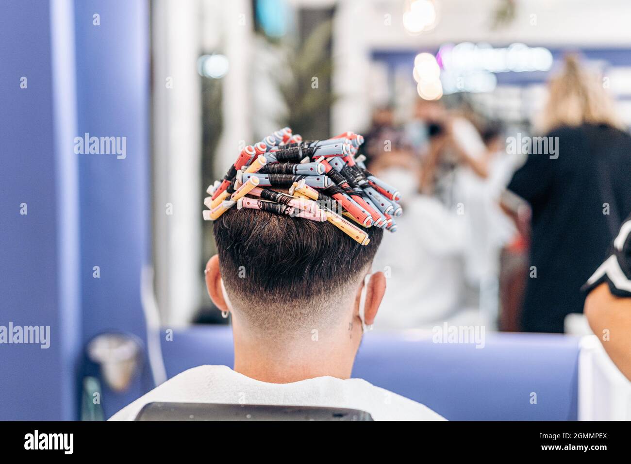 Testa di un uomo pieno di rulli per tingere i capelli in un salone Foto Stock