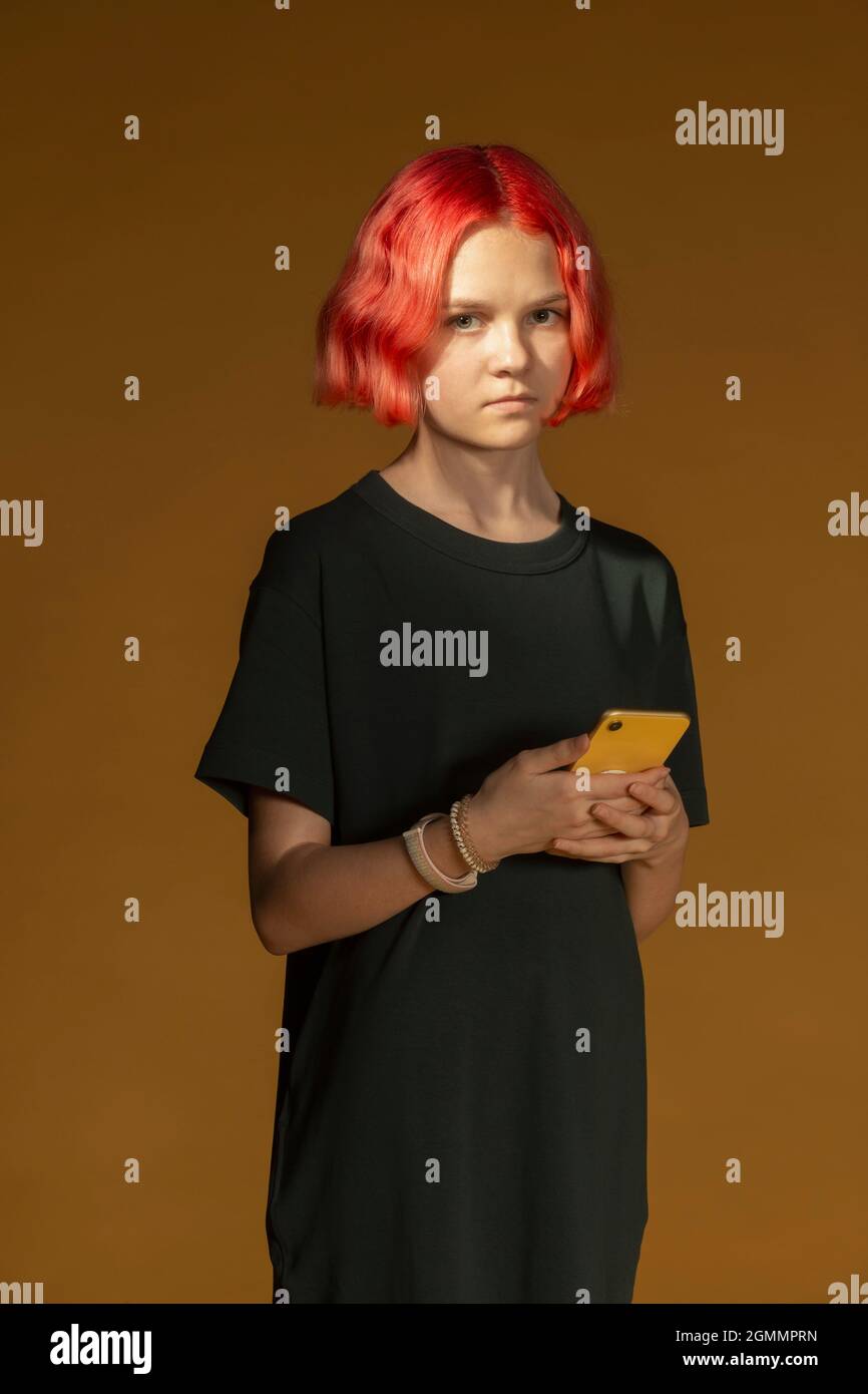 Ritratto seria ragazza adolescente con capelli rossi tinti tenendo smartphone Foto Stock