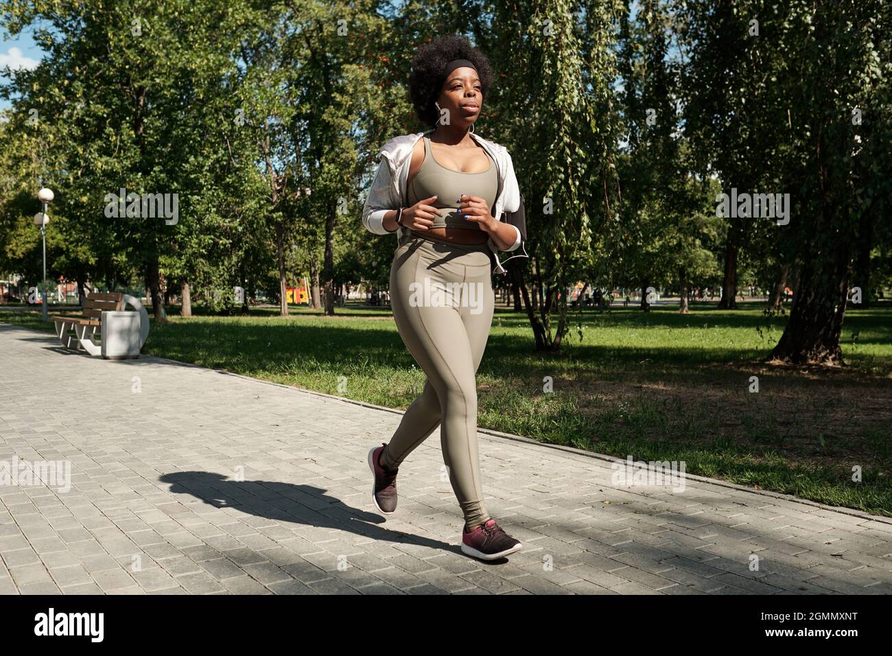 Giovane e giovane contemporanea, oltre a una donna africana in abbigliamento sportivo, jogging nel parco la mattina di sole Foto Stock