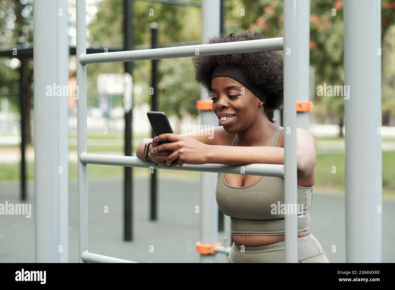 Uno sportivo sorridente in outdoor texting per l'abbigliamento sportivo in smartphone dopo l'allenamento all'aperto Foto Stock
