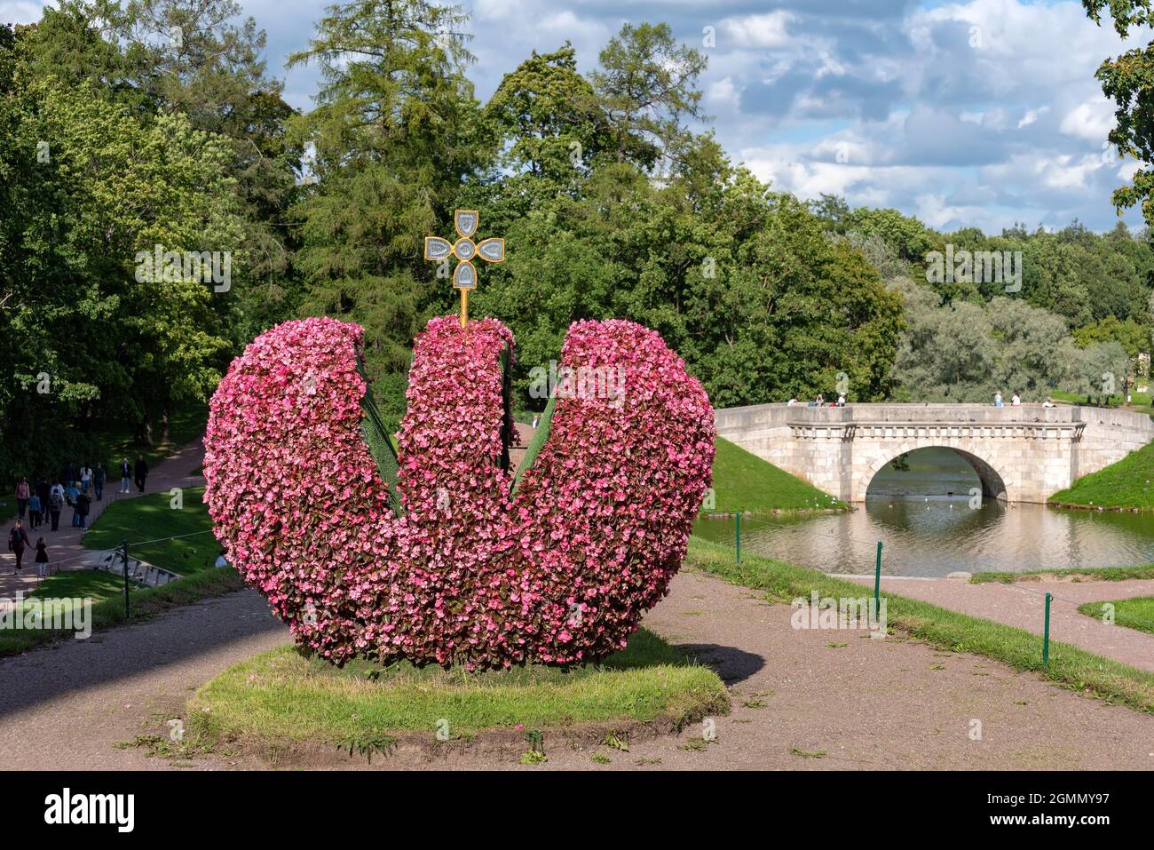 GATCHINA, Regione di Leningrado, Russia - 18 agosto 2021: Scultura in fiore della corona imperiale e il Ponte Carp e lo Stagno Carp sullo sfondo. Foto Stock