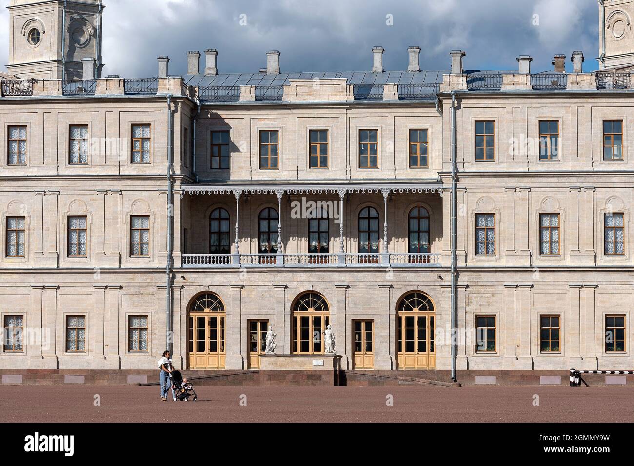 GATCHINA, Regione di Leningrado, Russia - 18 agosto 2021: Una donna con un bambino in una carrozza per bambini corre sulla piazza vicino al Grande Palazzo Foto Stock