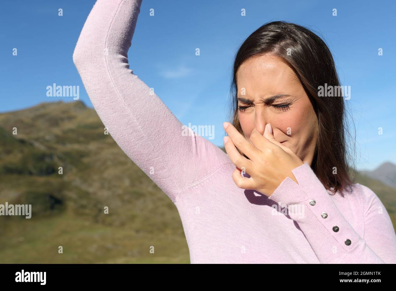 Donna casual puzzare stinky ascella in montagna una giornata calda Foto Stock