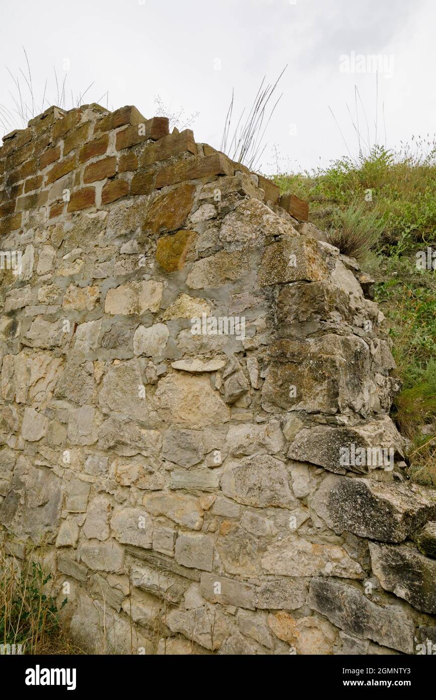Muro di pietra di rovine di materiali diversi. Il muro distrutto di una fortezza. Foto Stock